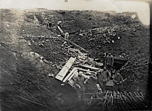 Historische Postkarte mit Soldaten in einem von Granaten zerstörten Schützengraben