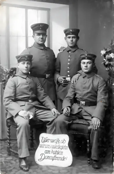 Fotografie von vier sich ähnlich sehenden Soldaten mit Blumensträußen auf Tischen.